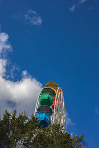 Low angle view of ferris wheel by building against sky