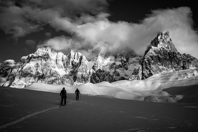 People walking on snowcapped mountain against sky