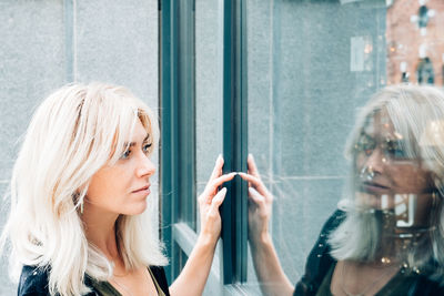 Portrait of young woman looking through window