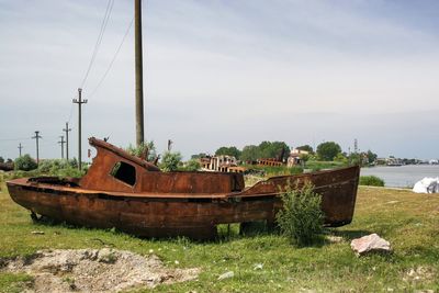 Abandoned boat moored at shore against sky