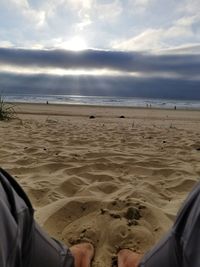 Low section of man on beach against sky