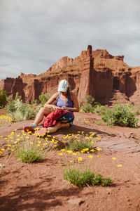 Female hiker sits down in yellow flowers at fisher towers moab utah