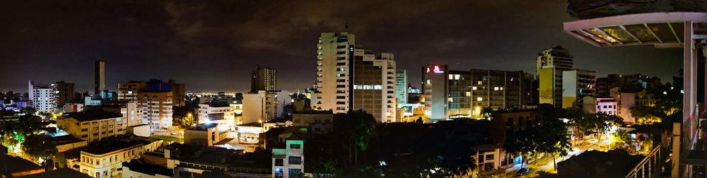 Illuminated buildings in city against sky at night