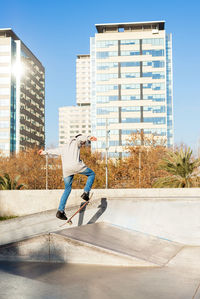 Young caucasian man jumping on a skateboard on skate ramp