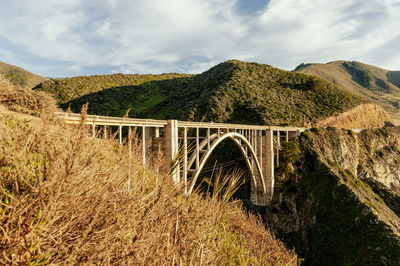 Arch bridge over mountains against sky