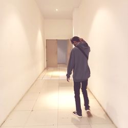 Rear view of man walking in corridor of building