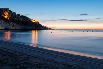 Scenic view of beach against sky at sunset