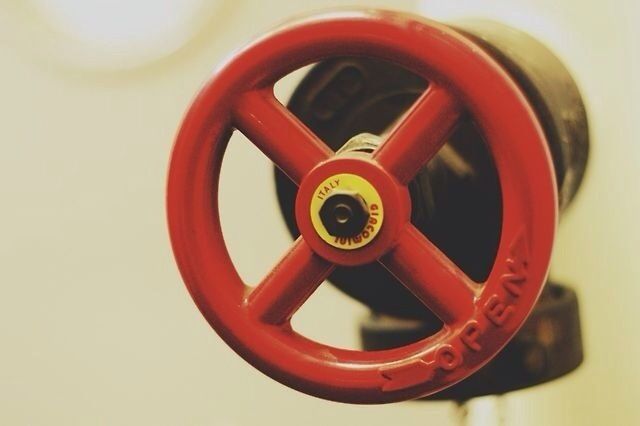 red, close-up, metal, indoors, circle, metallic, still life, single object, no people, geometric shape, safety, handle, wall - building feature, number, old-fashioned, man made object, protection, wheel, shape, technology