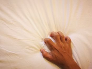Cropped hand of woman on bed