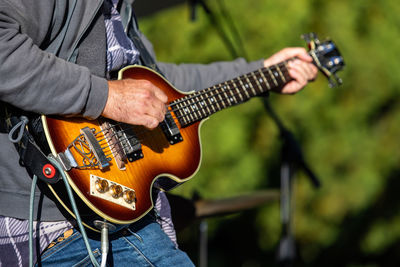 Midsection of man playing guitar