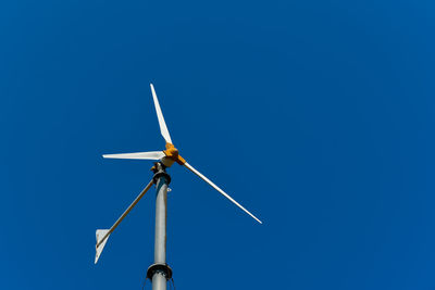 Low angle view of windmill against clear blue sky