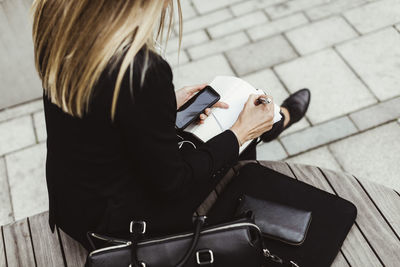 Low section of businesswoman writing while sitting outdoors