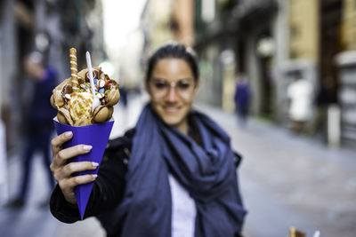 Portrait of smiling man holding ice cream in city