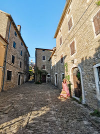 Young woman in pink dress in picturesque old town, village, summer, style, fashion.