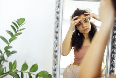 Portrait of young woman standing against wall