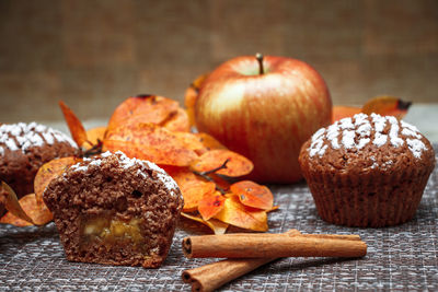 Chocolate muffins with apple filling on a background of autumn leaves and cinnamon