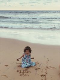 Girl playing with sand at beach during sunset