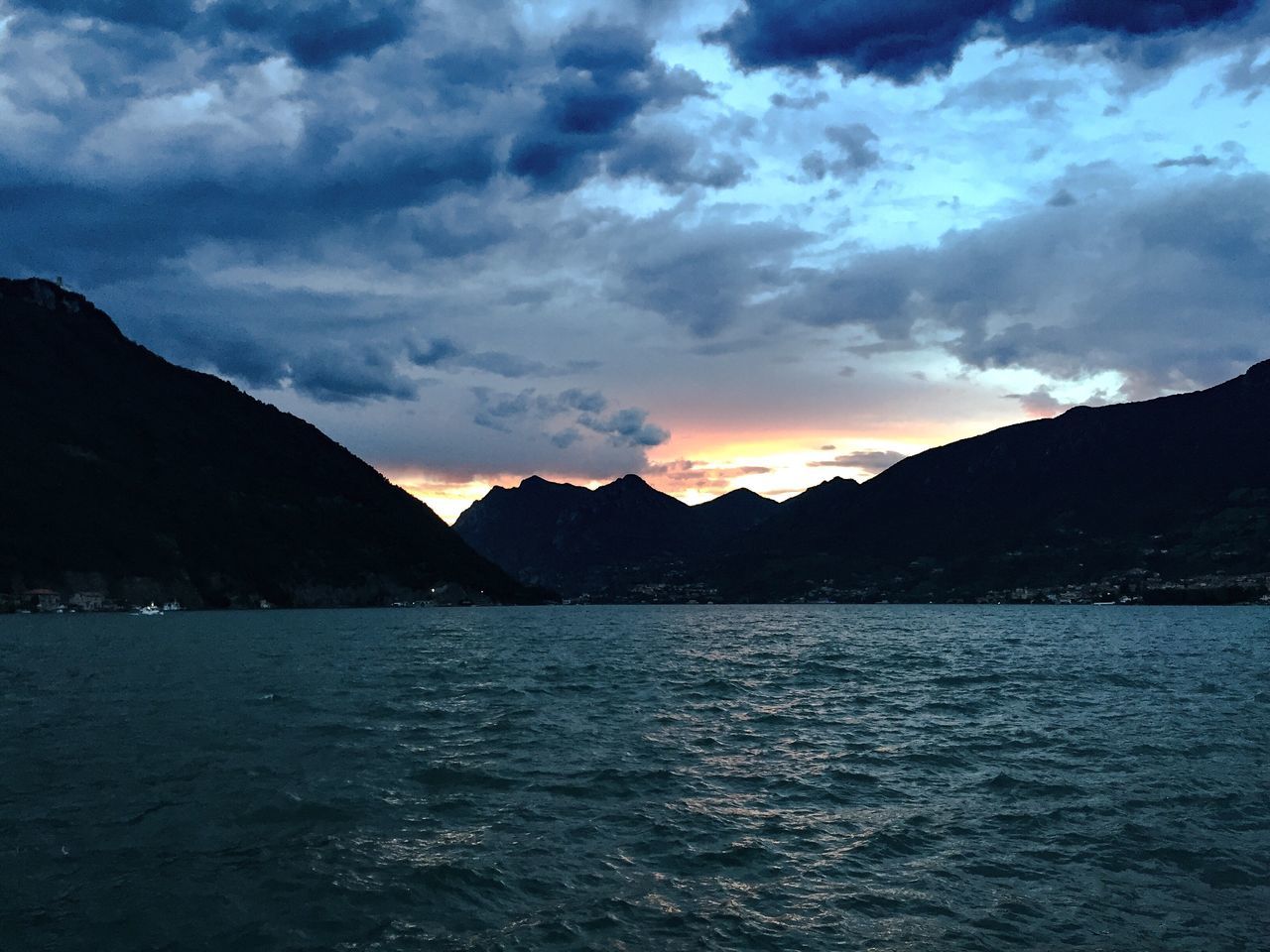 mountain, water, sky, scenics, tranquil scene, mountain range, tranquility, beauty in nature, cloud - sky, waterfront, sunset, lake, cloud, cloudy, nature, idyllic, rippled, dramatic sky, outdoors, non-urban scene, calm, majestic, no people, weather, remote, overcast, non urban scene