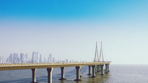 Pier over sea against clear blue sky