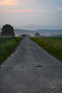 Road amidst field against sky