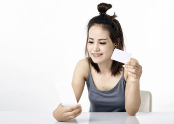 Young woman using smart phone against white background