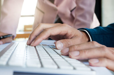 Cropped hands of man using computer while working with businesswoman