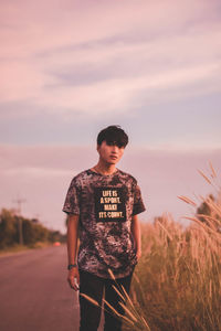 Boy standing on field against sky during sunset