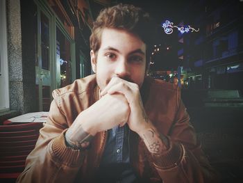 Portrait of young man sitting at sidewalk cafe