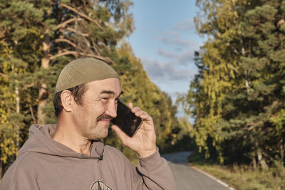 Man using mobile phone against trees