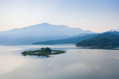 Scenic view of sea by mountains against sky