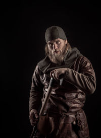 Serious viking with axe standing against black background