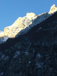 Low angle view of snowcapped mountains against clear sky