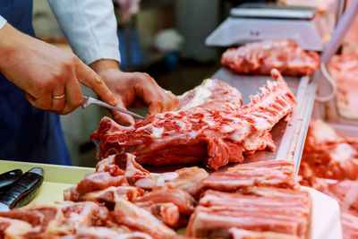 Cropped hands cutting meat at shop