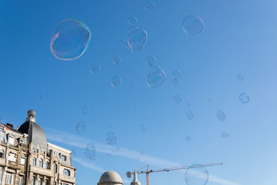 Low angle view of bubbles against blue sky