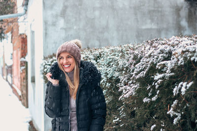 Portrait of smiling young woman standing in snow