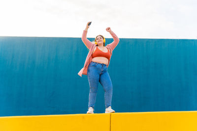 Happy young woman dancing and listening music