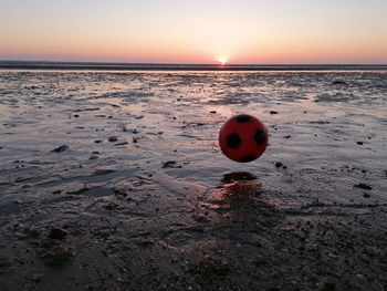 Scenic view of ball on beach against sky during sunset