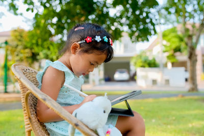Side view of young woman using mobile phone while sitting in park