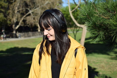 Portrait of beautiful young woman standing against plants