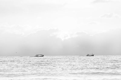 Mid distant view of boats sailing in sea against sky