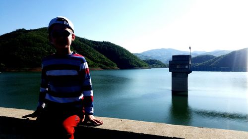 Rear view of man standing by lake against sky