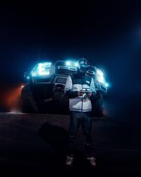 Man standing on illuminated street at night