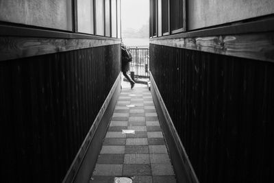 Rear view of woman walking on alley amidst buildings