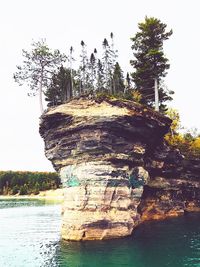 Low angle view of rock formation by river against sky