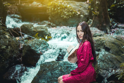 Woman standing by rocks in stream