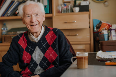 Portrait of smiling senior man sitting at home