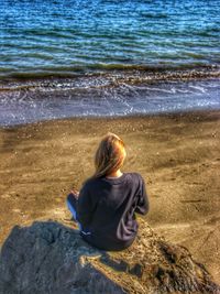 Rear view of woman sitting on beach