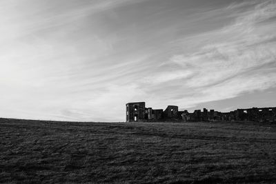 Abandoned building on field against sky