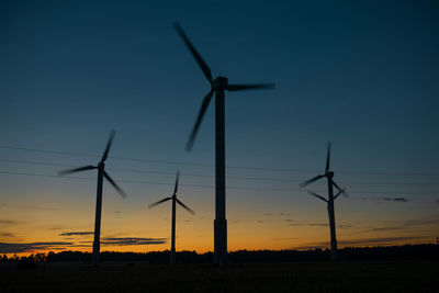 Power generators of windmills at shadow sunset - wind turbine on field at sunset