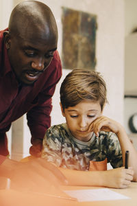 Male teacher assisting boys at desk in classroom